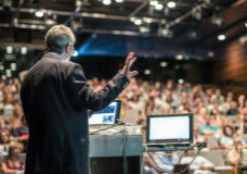 Speaker giving a talk on corporate business conference. Unrecognizable people in audience at conference hall. Business and Entrepreneurship event.